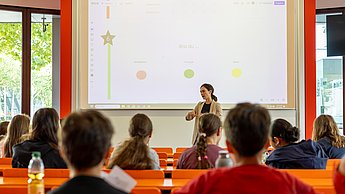 Kinder lernen Marktforschung. Professorin erklärt Fragestellungen zum Thema Eis.