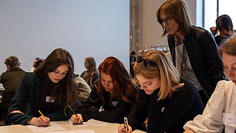 Studierende zeichnen Skizzen an einem Tisch
