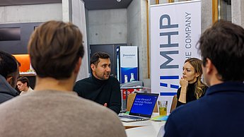 Mitarbeiter der Firma MHP mit Studierenden an einem Tisch