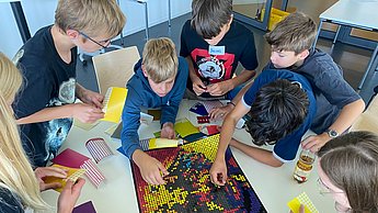 Kinder kleben mit Punkten Bilder von Einstein und Marie Curie