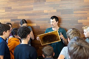 Wie entsteht eigentlich Bienenwachs? Hier zeigt Felix Bischoff den Kindern Gerätschaften dazu.