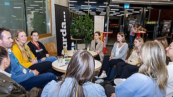 Studierendengruppe und Firmenvertreter an Tisch sitzend