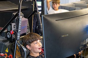 Ein Junge sitzt im Rennsimulator und lächelt.