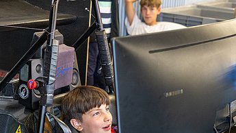 Ein Junge sitzt im Rennsimulator und lächelt.