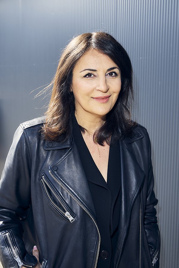Eine Frau mit Lederjacke lächelt in die Kamera (es ist Düzen Tekkal)