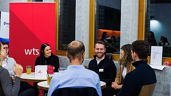 Studierende an einem Tisch im Austausch mit Unternehmensvertretern 