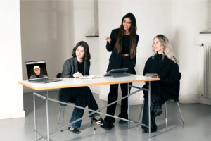 Studenten zeigen Mode an einem Laptop der auf einem Tisch steht.
