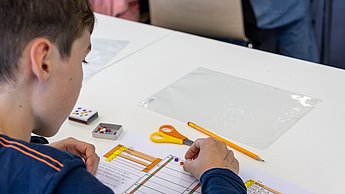 Ein Junge legt mit Smilies seinen Code und gibt dem Pen and Paper Computer so "Anweisungen"