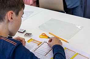 Ein Junge legt mit Smilies seinen Code und gibt dem Pen and Paper Computer so "Anweisungen"
