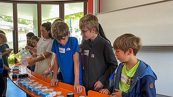 Kindergruppe schaut sich Lampenschirme aus dem 3D Druck an