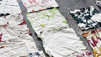 Stoffe mit verschiedenen Spritzmustern liegen auf dem Boden