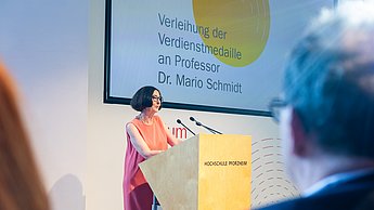 Professorin steht am Rednerpult.