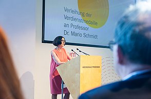 Professorin steht am Rednerpult.