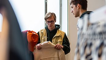 Zwei Studenten betrachten Kleidungsstücke