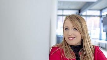 A woman leaning against a wall and smiling