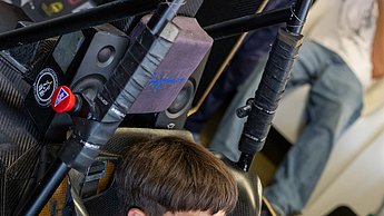 Ein Junge sitzt im Rennsimulator und lächelt.