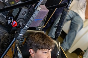Ein Junge sitzt im Rennsimulator und lächelt.