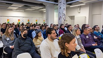 voller Saal mit Menschen, die einem Fachbeitrag lauschen