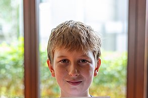 Junge zeigt selbstgebasteltes Bild in die Kamera