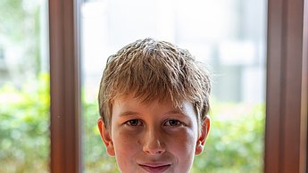 Junge zeigt selbstgebasteltes Bild in die Kamera