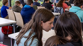 Zwei Mädchen besprechen die Lösung untereinander