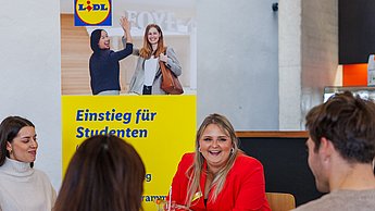 Mitarbeiterin von Lidl im Gespräch mit Studierenden