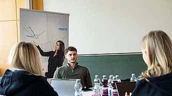 Ein Student mit Mitarbeiterinnen von Festo an einem Tisch