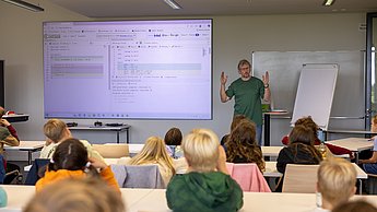 Vorne spricht der Dozent, während die Kinder gespannt zuhören
