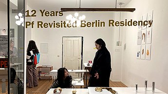 Personen im Gebäude mit Aufschrift "12 Years - Pf Revisited Berlin Residency"