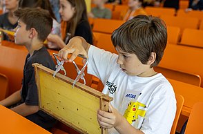 Kinder schauen sich Bienenwaben und Utensilien zur Imkerei an.