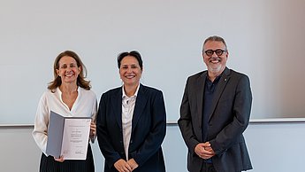 Gewinnerin, Moderatorin und Laudator bei der Preisverleihung