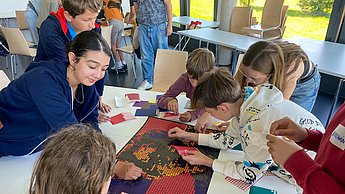 Kinder beim gemeinsamen Kleben der Punkte auf Marie Curie