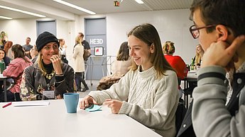 Menschen sitzen in Kleingruppen am Tisch und tauschen sich über ihre Ideen aus