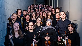 Die Besatzung des Hochschulorchesters posiert für ein Gruppenfoto.