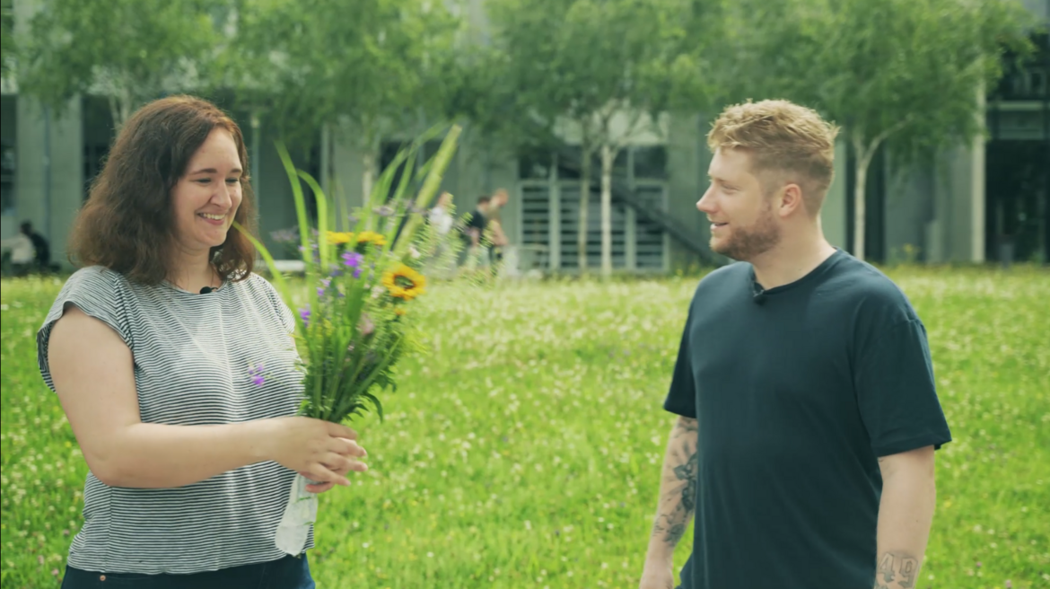 Alexandra Voigt mit Blumenstrauß neben Kevin Gerwin vor grüner Wiese