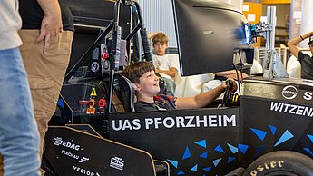 Ein Junge sitzt im Rennsimulator und lächelt.
