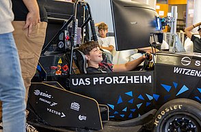 Ein Junge sitzt im Rennsimulator und lächelt.