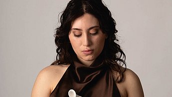 Foto einer Frau in einem Kleid, die eine kleine Kiste auf der Hand hält