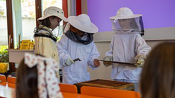Im Workshop mit Felix Bischoff konnten die Kids in die Welt der Imkerei schnuppern und dabei selbst in Imkeranzüge schlüpfen und versuchen eine leere Wabe aus einer Bienenbeute zu holen.