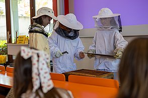 Im Workshop mit Felix Bischoff konnten die Kids in die Welt der Imkerei schnuppern und dabei selbst in Imkeranzüge schlüpfen und versuchen eine leere Wabe aus einer Bienenbeute zu holen.