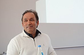 Gunjan Bhardwaj, Alumnus der Business School Pforzheim und heutiger CEO von Partex.AI N.V., steht in einem weißen Pullover am Pult des Hörsaals