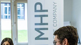 Ein Studierende an einem Tisch mit einer Vertreterin von MHP A Porsche Company