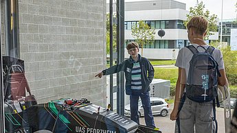 Ein Kind schaut sich fasziniert einen der Rennwägen an, der an der Fakultät für Technik steht.