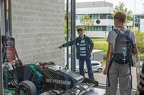 Ein Kind schaut sich fasziniert einen der Rennwägen an, der an der Fakultät für Technik steht.