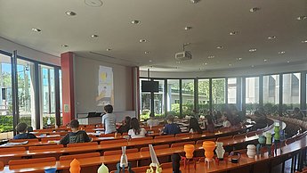 Hörsaal, in dem unterschiedliche Lampenschirme im Raum zur Demonstration aufgestellt sind.