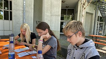 Kinder schreiben etwas auf Zettel
