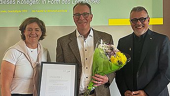 Preisträger Prof. Dr. Robert Nothhelfer mit Urkunde und Blumenstrauß, rechts neben ihm steht Prof. Dr. Thomas Cleff