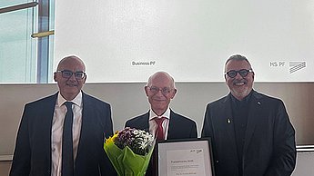 Preisträger Prof. Dr. Andreas Willburger mit Urkunde und Blumenstrauß, links davon Prof. Anush Tavakoli, rechts Prof. Dr. Thomas Cleff 