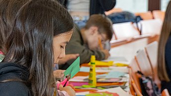 Viele Scheren und Kleber, die von Kindern bedient werden