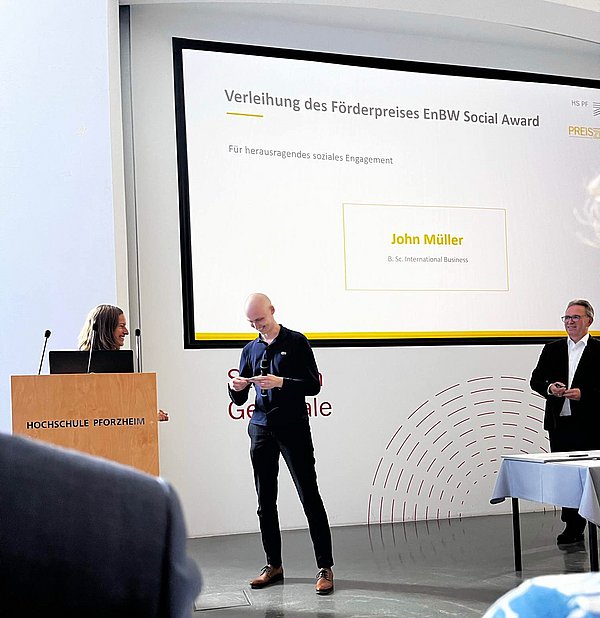 Junger Mann bekommt einen Förderpreis verliehen und lächelt in die Kamera